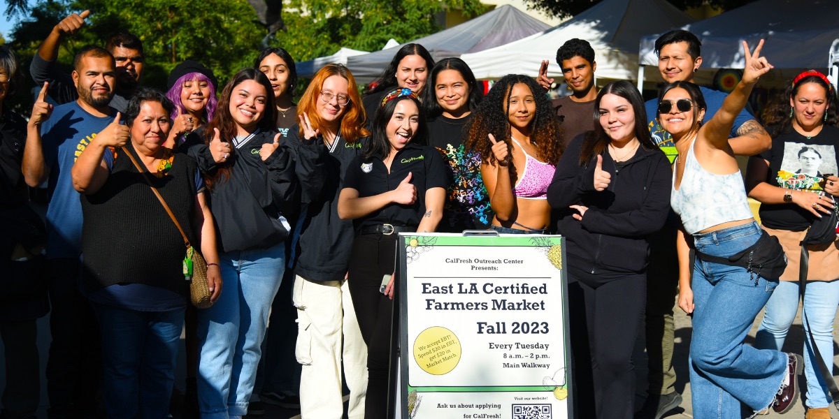 A group of people posing for a picture at the farmers market