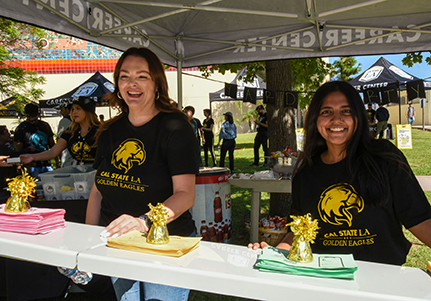 Two staff members in matching Cal State LA t-shirts standing in a Career Center canopy.