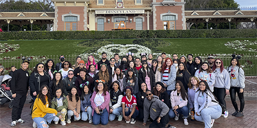 A large group of people in front of a building in Disneyland.