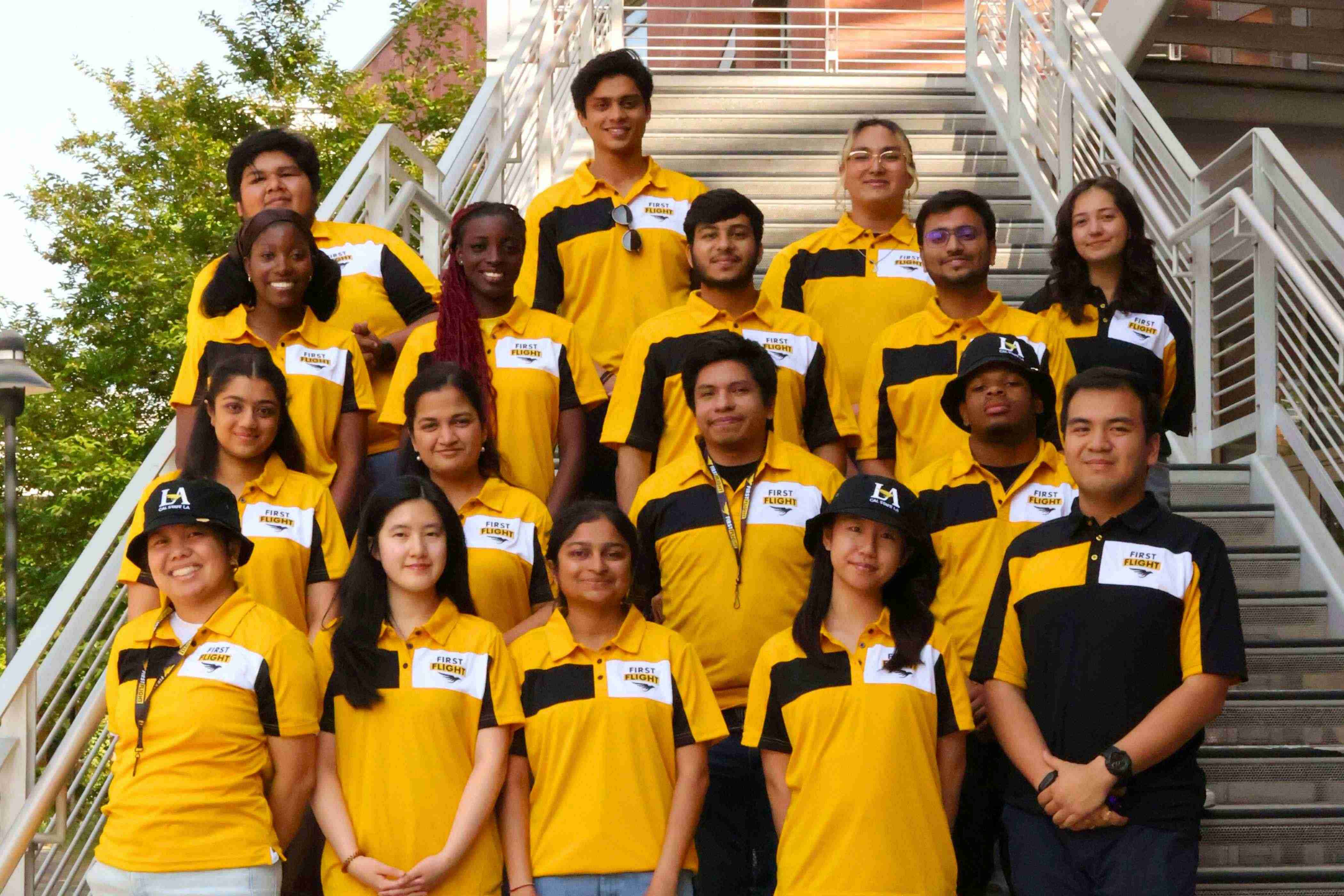 Students with yellow and black polo shirts that read "First Flight" on them, standing in rows atop of a staircase.