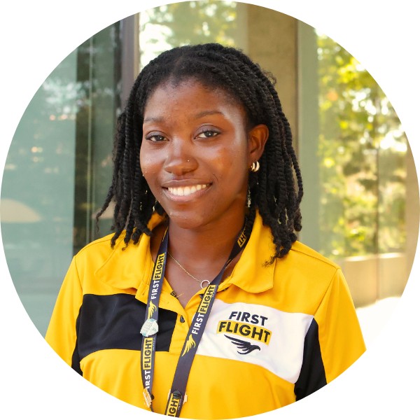 A black woman with a yellow and black polo smiling toward the camera.
