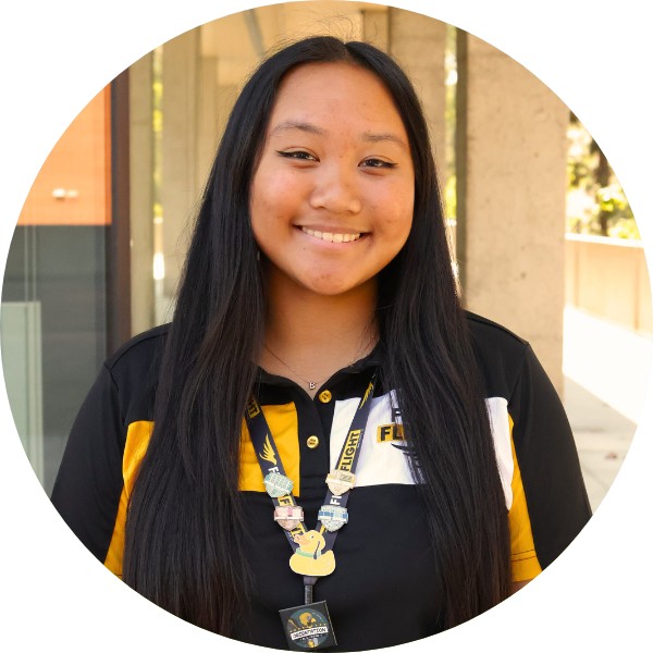 A woman with black hair and a black polo smiling at the camera.