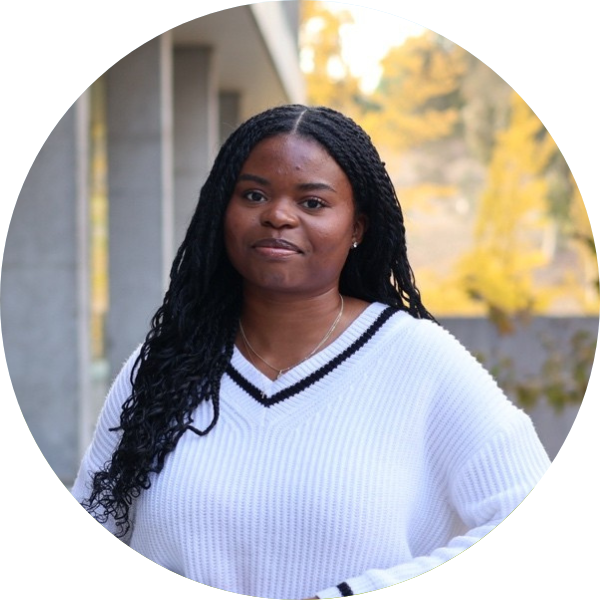A woman with a white sweatshirt and braided hair smiling at the camera.