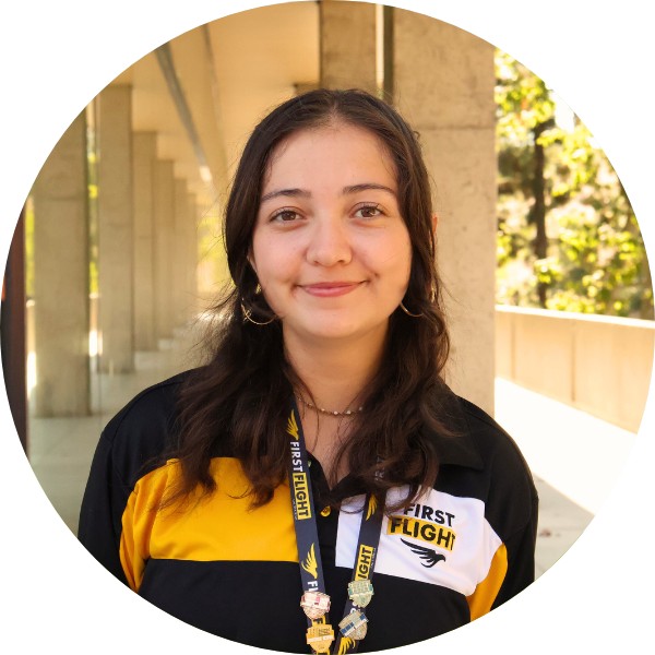 A woman with brown hair and a black polo smiling at the camera.