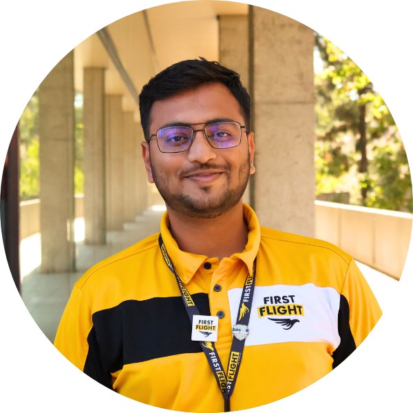 A man with a yellow and black polo that reads "First Flight" staring into the camera.