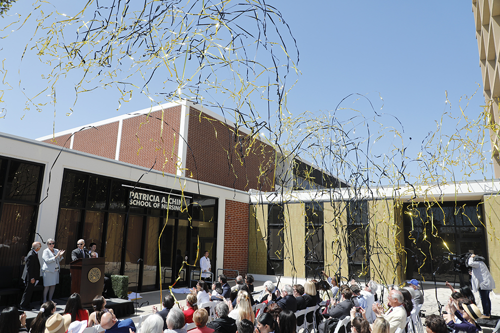 The crowd cheers as black and gold streamers shoot into the air after the officially naming of the school. 