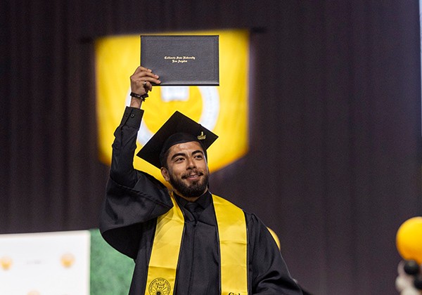 Graduate holding his diploma above his head