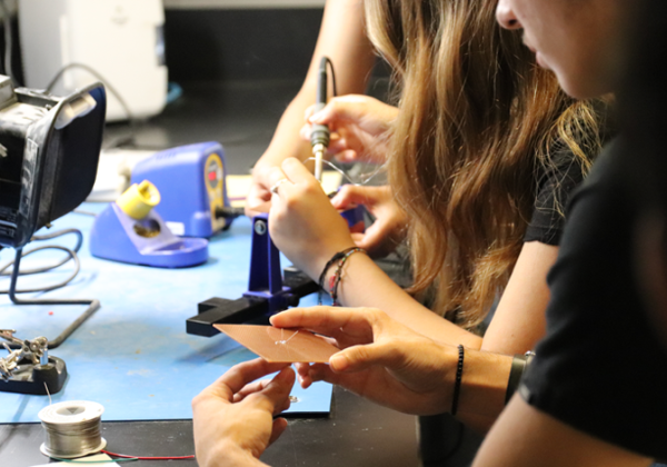 closeup of student hands holding electronic components in lab