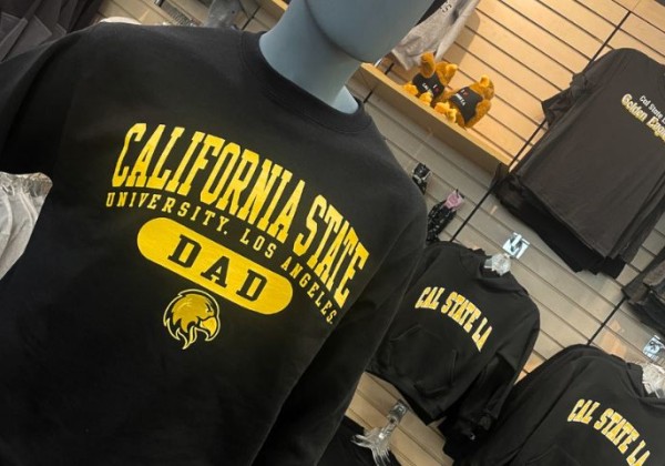 A display of merchandise featuring a black sweatshirt with yellow lettering that reads “California State University Dad,” 