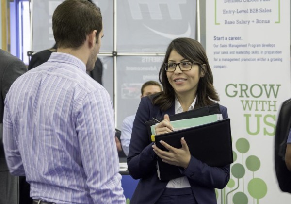 Student in professional clothes talks to an employer at the career fair.
