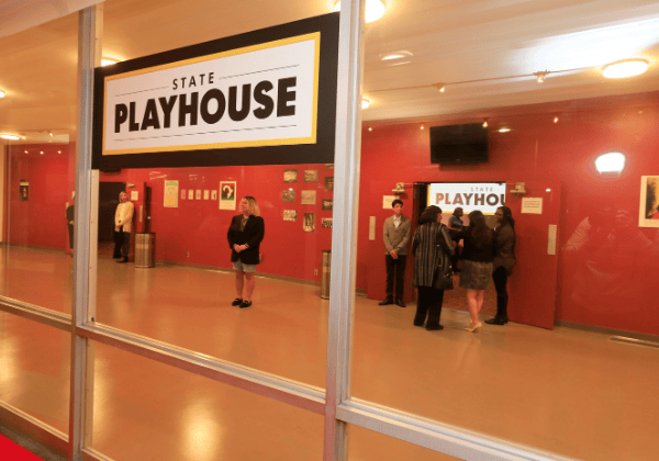Looking through the windows into the lobby of the Cal State LA State Playhouse. There are people milling about.