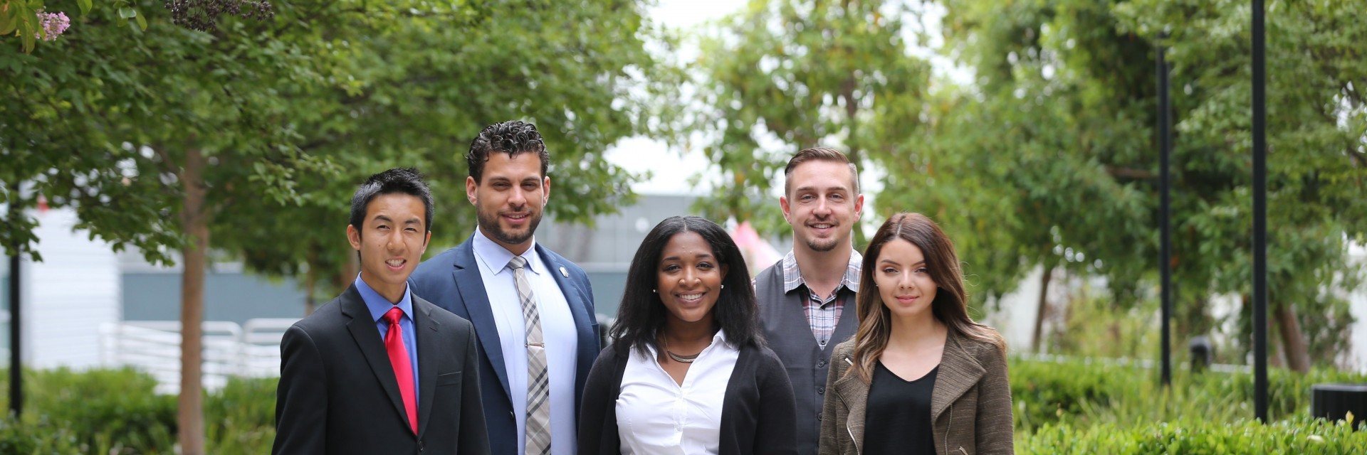Students in professional clothing stand confidently outside.