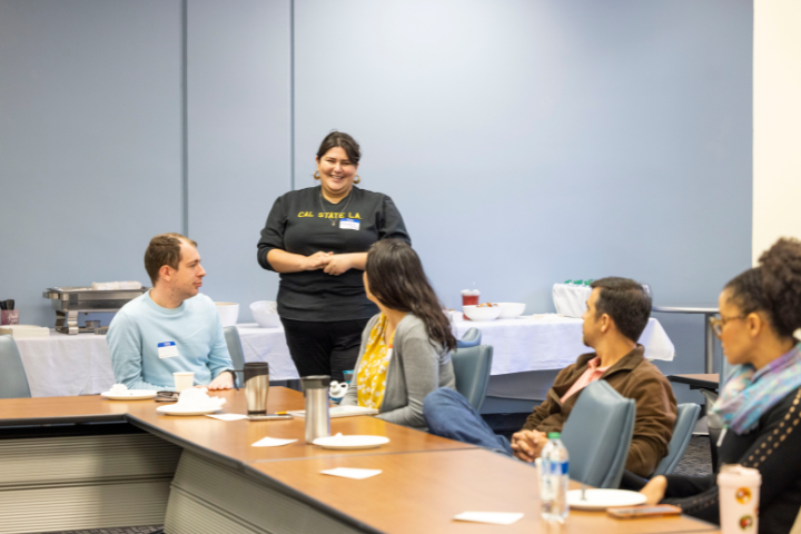 Woman smiling and talking to a group of people seated at a desk