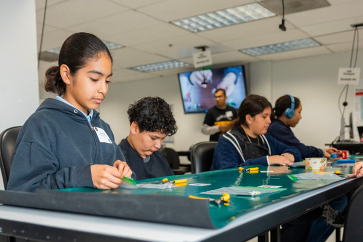 middle school students work on engineering project on a table inside lab