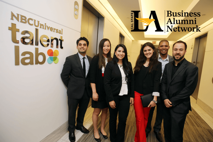 Six people posing and smiling in a hallway next to a sign that says NBC Universal Talent lab. Additional text says Cal State L.A. Business Alumni Network