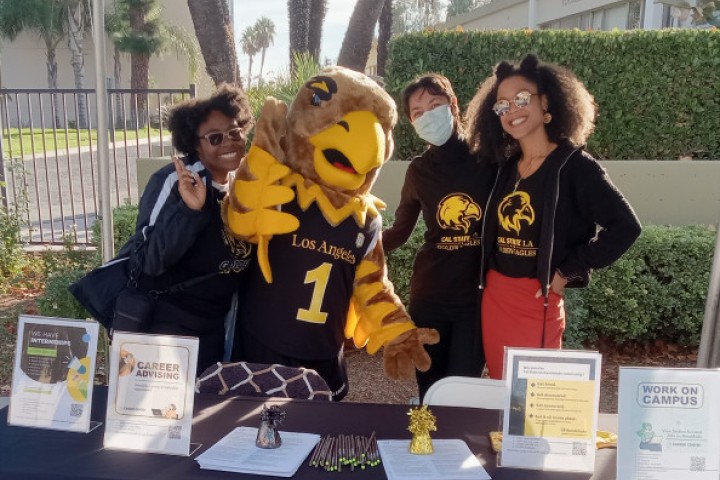 Career advisors, students, and campus mascot Eddie smile outside the Career Center.
