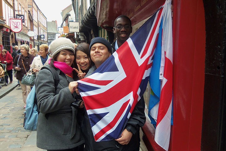 Three students holding a UK flag