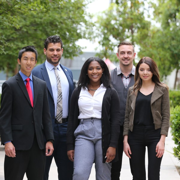 Students in professional clothing stand confidently outside.