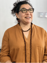 Maria Ambriz wearing beaded necklace and brown shirt