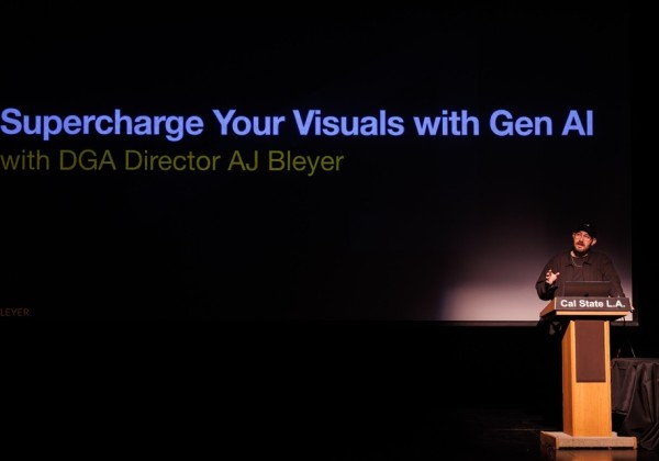 Presenter standing at a Cal State LA podium in a dark auditorium with a large screen reading “Supercharge Your Visuals with Gen AI with DGA Director AJ Bleyer.