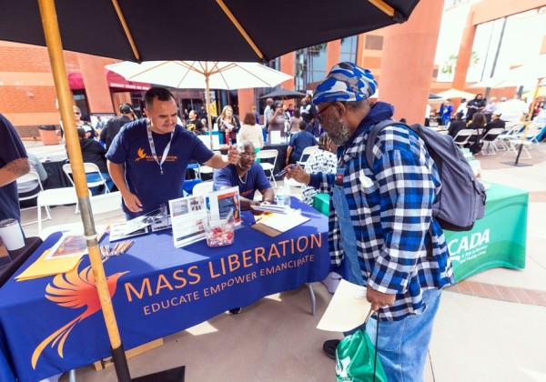 Community member speaks with representatives at an outdoor resource table during a campus event at Cal State LA.