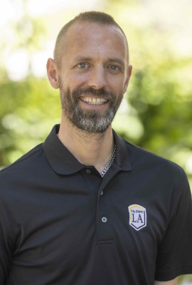 Mitch Fryling in a sunny courtyard area with trees