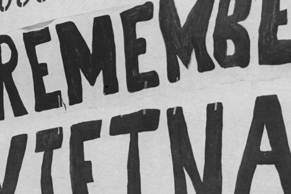 A speaker giving a speech in front of a Remember Vietnam sign